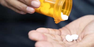 A person pours pills into their hand