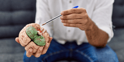 Young man holding brain having psychology session at clinic