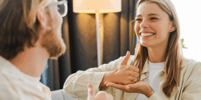 Young woman on a cozy couch signs with her therapist, showing empathy and connection in mental health counseling. The therapist listens attentively, creating a safe space. Sign language concept