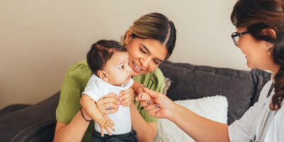 Doctor visiting young mother at home for routine checkup of the newborn